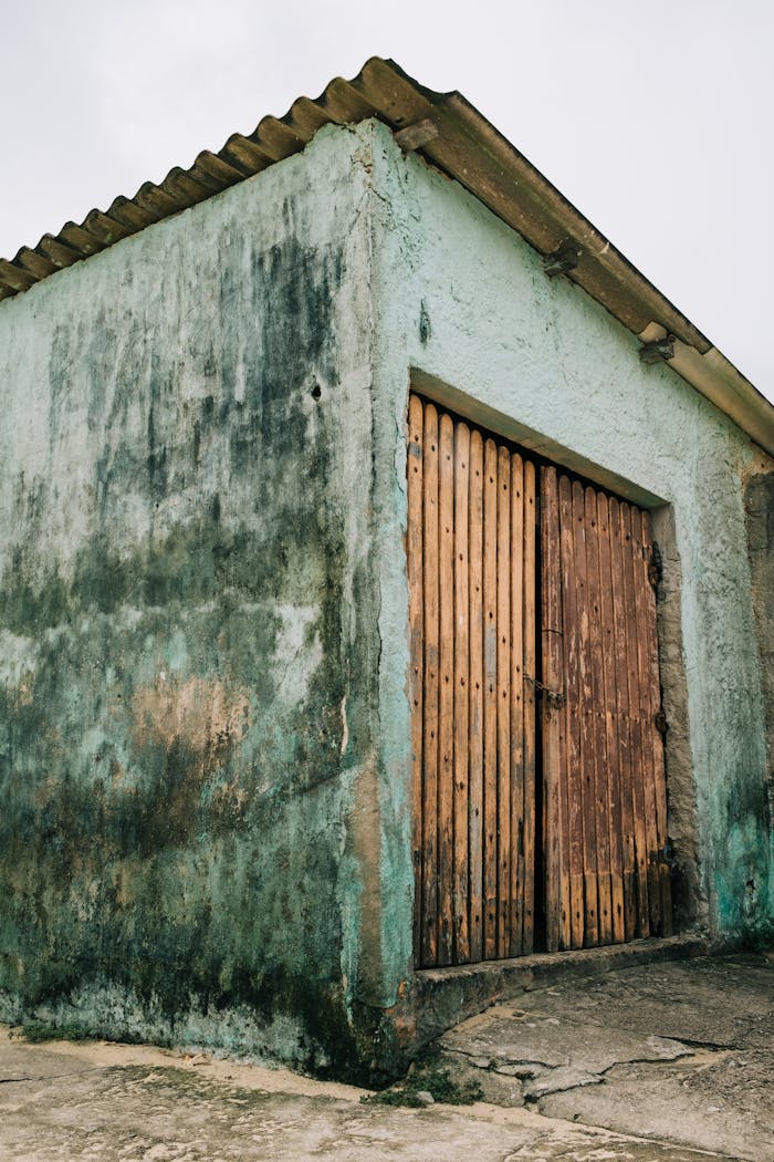 A vintage storage shed in Angra dos Reis with a wooden door and weathered walls.